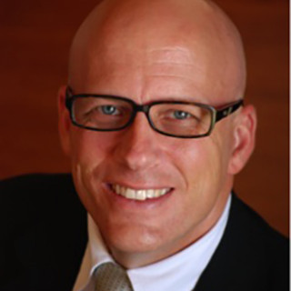 Brian Dille wearing glasses, white shirt, black jacket and tie