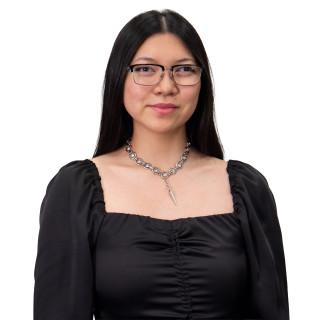 Woman wearing a black dress, necklace and wearing glasses.