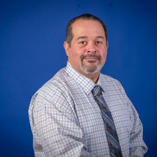 Gabriel Sinohui with plaid dress shirt and tie with a blue background.