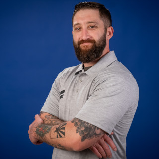 Man in gray polo shirt with arms crossed against chest